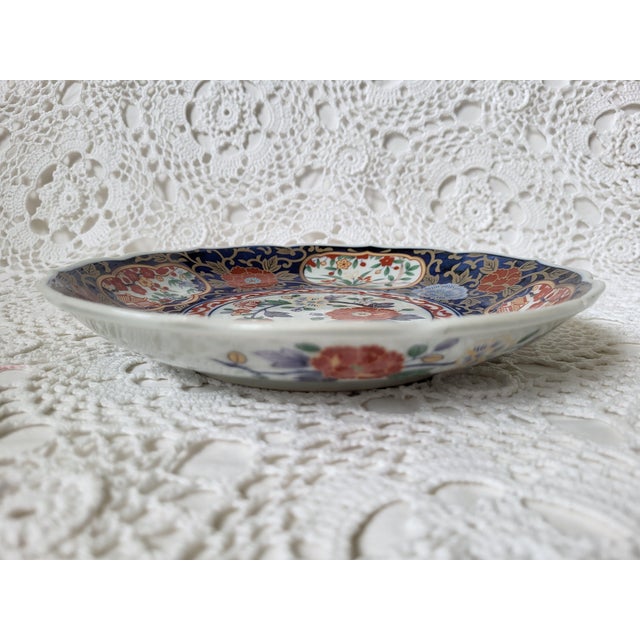 An Imari style plate or shallow bowl from Arita, Japan. In the traditional colors, red, blue and gold. It measures 8 ¾”...