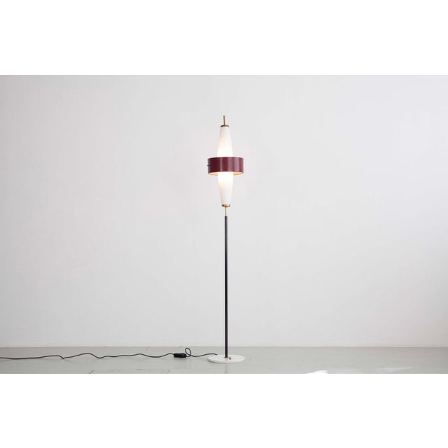 Floor lamp, Italy, 1950s. The lamp features a black lacquered iron frame with a brass and marble base, and a frosted glass...