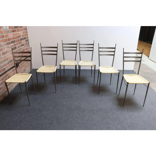 Set of six Italian steel dining chairs with brass finials/accents and beige handwoven plastic seats (ca. 1950s, Italy). A...