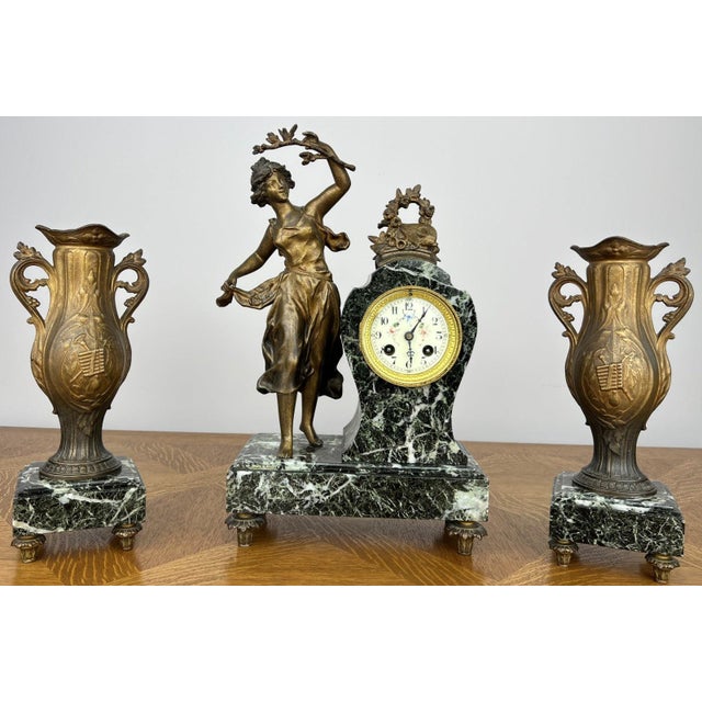 A beautiful Vintage French garniture set featuring an ornate marble clock accompanied by matching decorative side...
