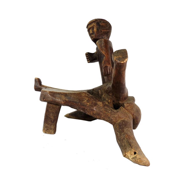 An extraordinary three-legged chair. A stylistically carved figure straddles the stool with arms carved to hug the...