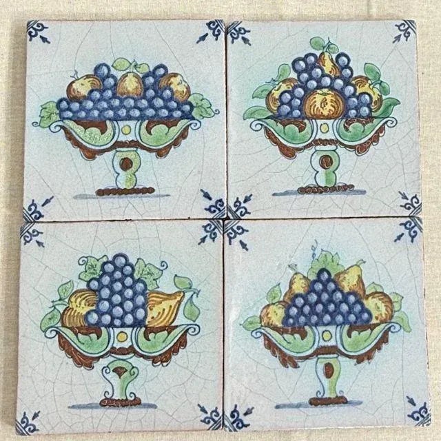 A timeless set of four (4) 19th-century Dutch Delft tiles with unique variations of fruit baskets that include grapes,...
