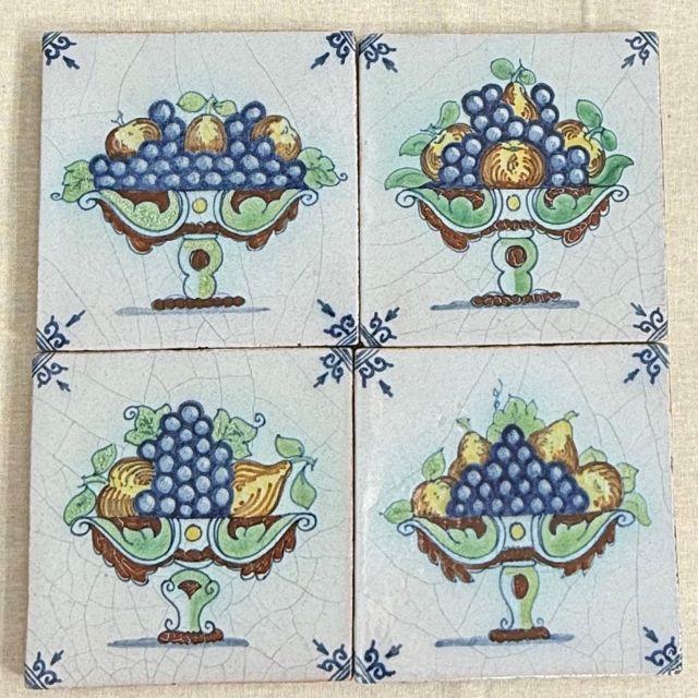 A timeless set of four (4) 19th-century Dutch Delft tiles with unique variations of fruit baskets that include grapes,...