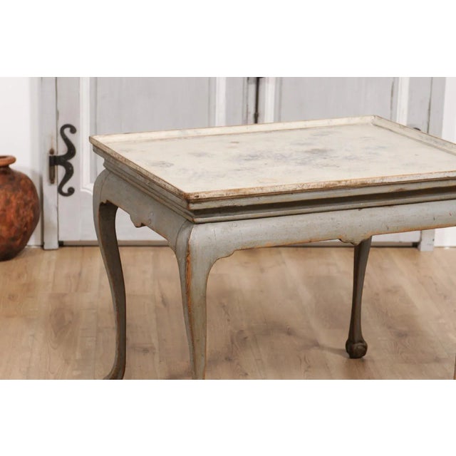 A Swedish Rococo period tea table from circa 1750 with gray painted finish, tray top, cabriole legs and ball and claw...