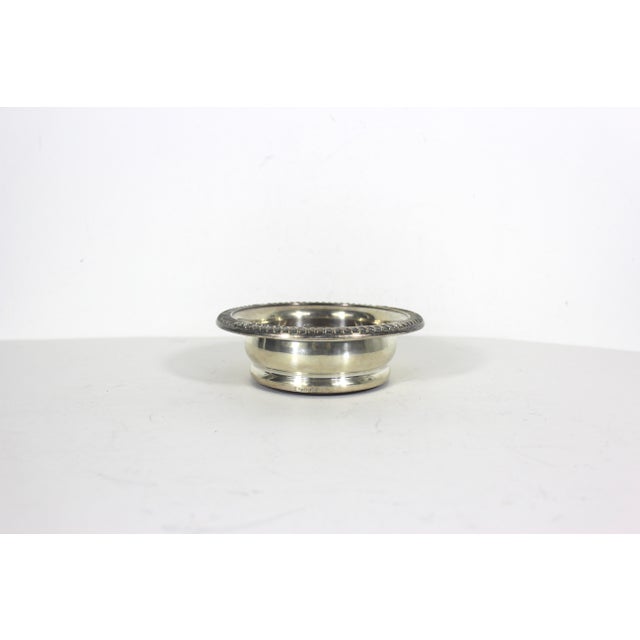 Vintage silver plated wine bottle coaster with wood base. This has tarnish and patina. This fits a wine bottle or could be...