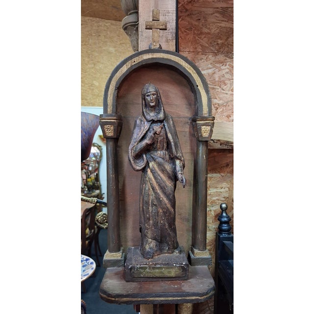 A carved wooden devotional statue of the Virgin Mary with the Sorrowful and Immaculate Heart, displayed in an...