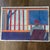 Original pastel drawing featuring a graphically drawn scene and artist. Bright cobalt blue, reds and orange are featured....