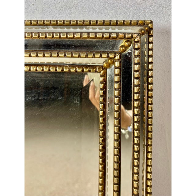 Elegant wall mirror featuring a sophisticated brass frame with decorative beaded detailing and beautifully beveled...