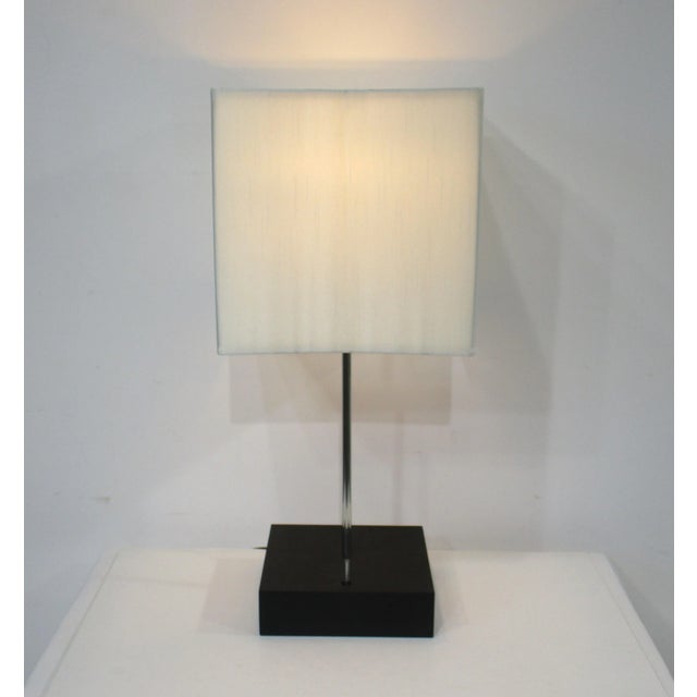 A mid century table lamp with satin black wood base , aluminum twist switch that has a dimmer topped with a silk blend...