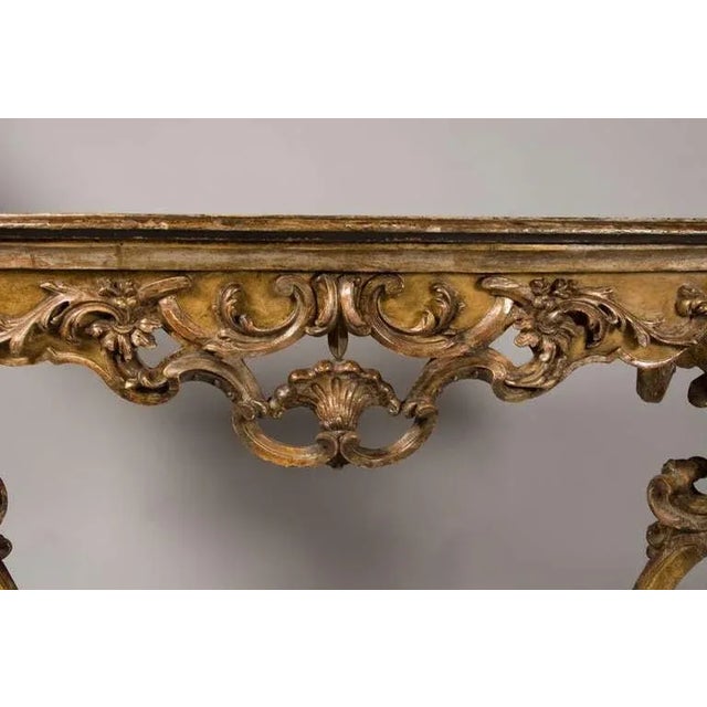 An Italian giltwood and ochre painted console, with doe foot detail. Fabulous flamboyant carving indicative of the Italian...