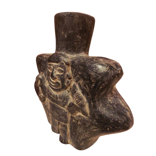 The sculptural design features a stylized Andean ceremonial figure with an elaborate headdress, expressive facial...