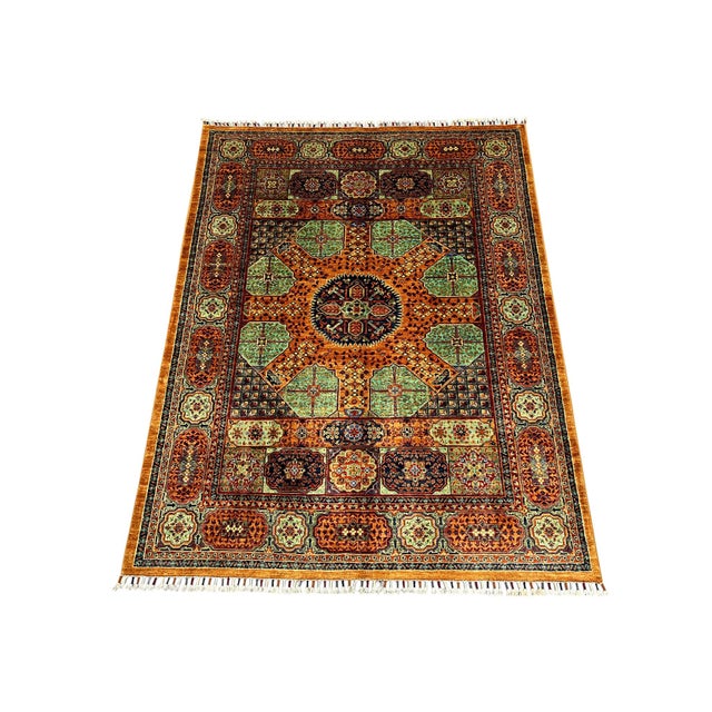 This naturally dyed wool rug features a Mamluk-inspired design in warm orange, teal, navy, and ivory. A dark central...