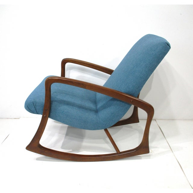 A walnut toned sculptural wood framed rocking chair reupholstered in a nice tightly woven blue Knoll contract fabric....