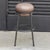 An iron tubular (25mm) structured armchair. Seat upholstered in brown leather. The leather upholstery oozes over the bare...