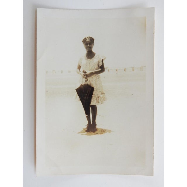 Mid 20th century sepia toned silver gelatin snapshot photograph of young African American girl in pretty ruffled dress...