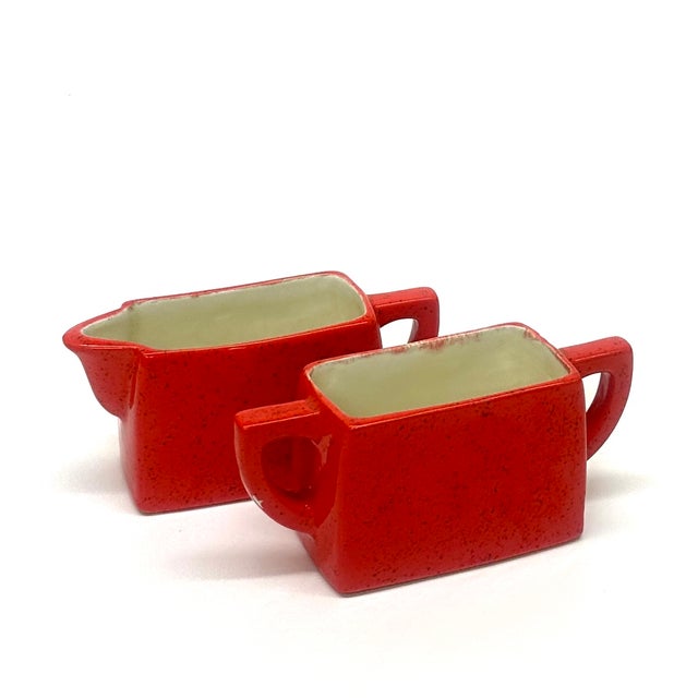 Artisanal red sugar bowl & creamer set. This mid-century ceramic sugar bowl and creamer set features a vibrant red glaze...