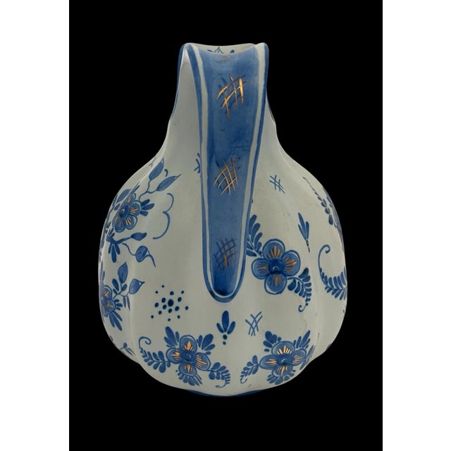 This rare vintage Delvo Holland Delft handpainted water pitcher is a beautiful piece of pottery featuring a blue and gold...