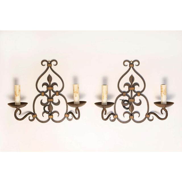 This striking pair of 20th-century French sconces showcases the elegance of wrought iron craftsmanship, beautifully...