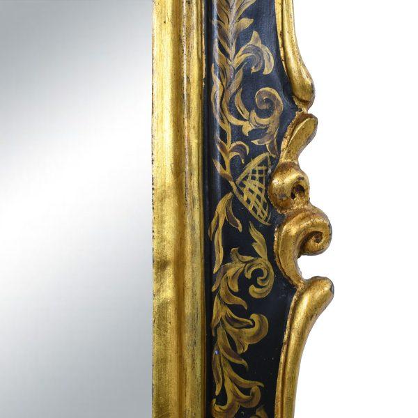 A dramatic chinoiserie mirror in black and gold — glossy black framing with gilded Oriental detailing that glows against...