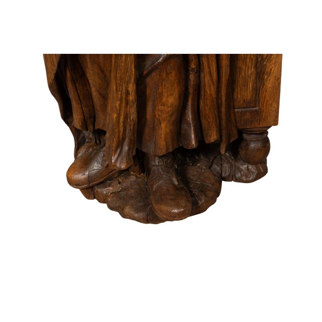 Large figure standing with a book under his arm with hand extended.