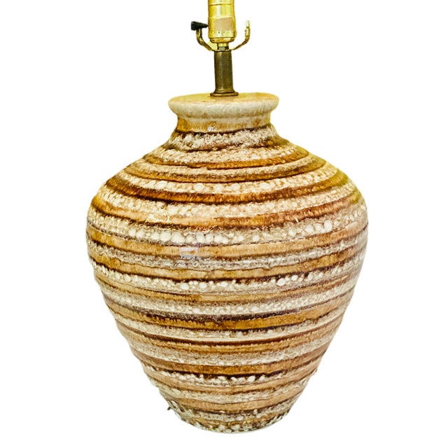 A large 1960's Mid-Century Modern pottery table lamp with fat lava glaze in tones of brown, tan, and cream. The glaze was...