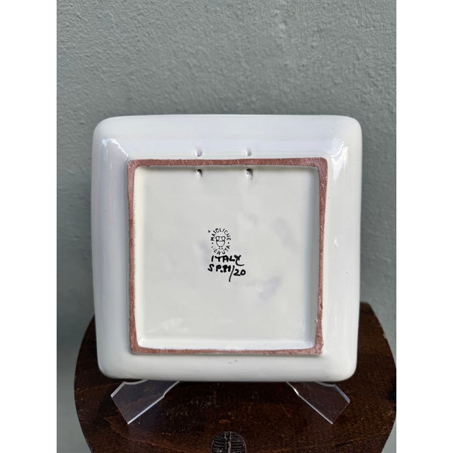A beautifully hand-decorated square maiolica dish featuring an exquisite sgraffito design — the ornate pattern scratched...