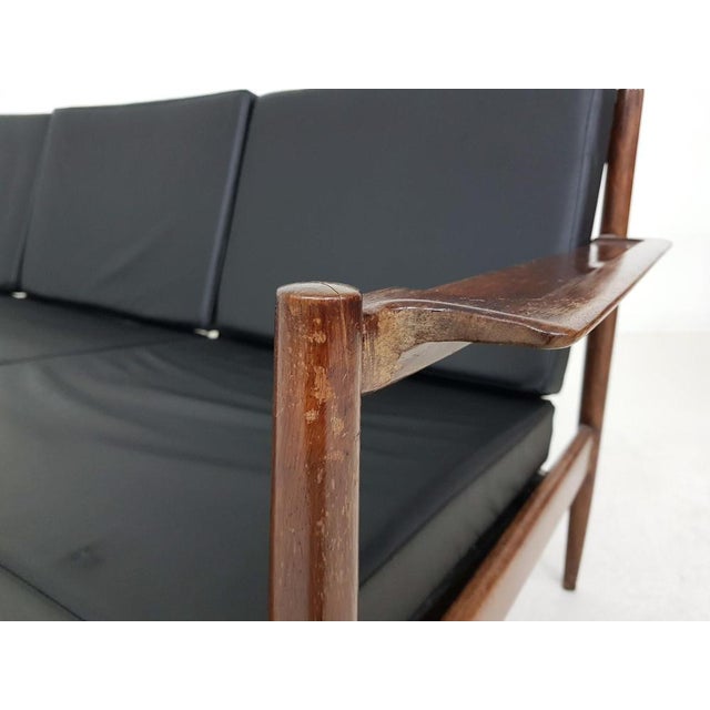 Wooden sofa with black vinyl upholstery. Wooden sofa with six cushions with black vinyl upholstery. Two springs are a...