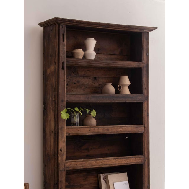Splendid primitive cabinet in solid Swiss pine with five shelves. Organic shape with decorative frames. Recovered in...