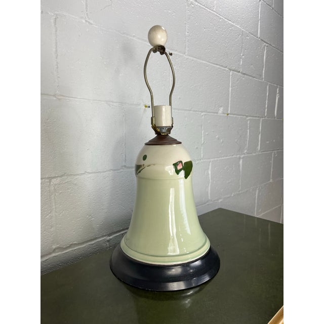 A charming vintage ceramic table lamp featuring a softly tapered bell-form body finished in a warm ivory glaze. Hand-...