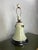 A charming vintage ceramic table lamp featuring a softly tapered bell-form body finished in a warm ivory glaze. Hand-...