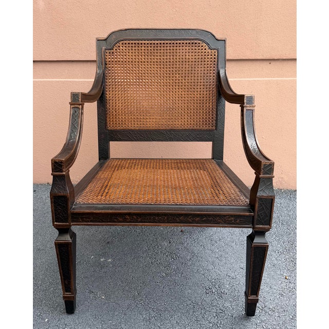 Vintage Baker Milling Road armchair featuring a distinctive dark lacquered finish, intricately caned back and seat, and an...