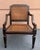 Vintage Baker Milling Road armchair featuring a distinctive dark lacquered finish, intricately caned back and seat, and an...