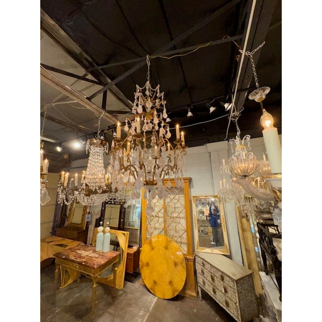 This antique French chandelier features a luxurious design with gilt iron and rock crystal accents, evoking a sense of...