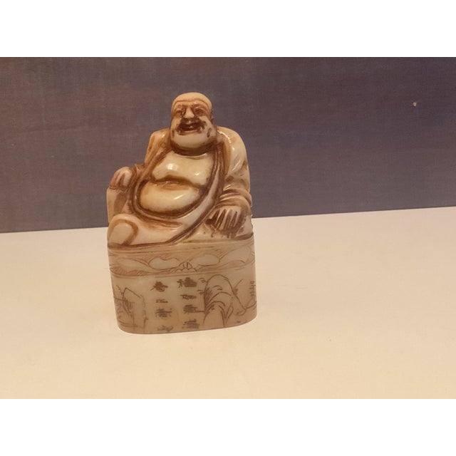 Cheerful hand‑carved figure of Budai, known as the Laughing Buddha, seated in relaxed repose. The piece features smooth...