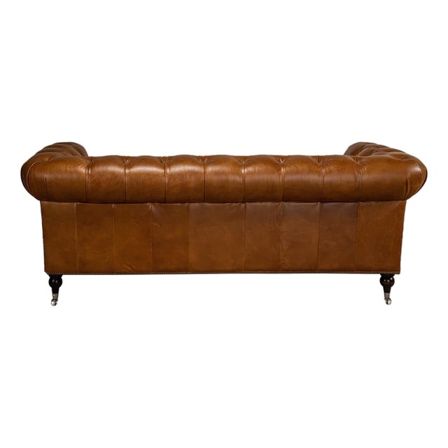 Top-grain leather in a vintage Cuban cigar tone covers an English sofa with a tufted backrest and rolled arms. Two padded...