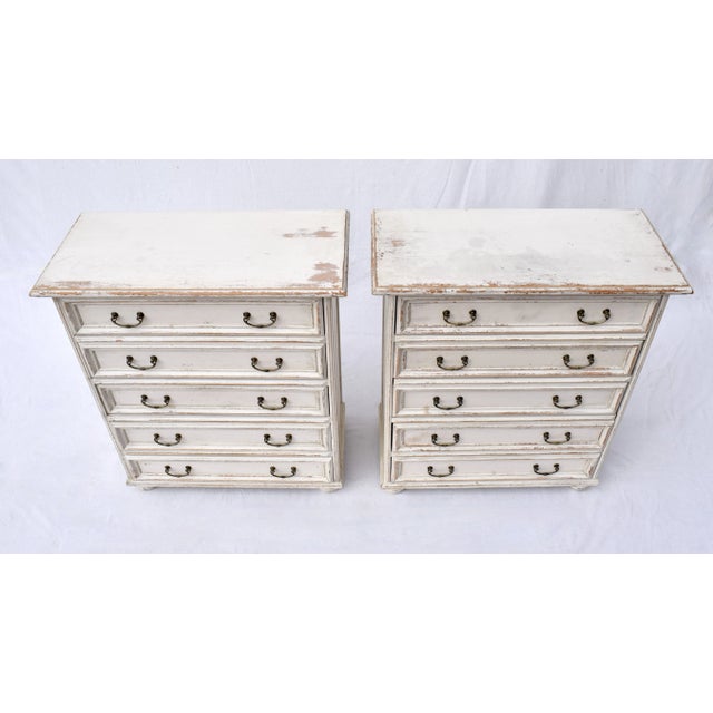 A pair of chests of five paneled drawers with bun feet & brass pulls made in Italy by Buying & Design boasting...