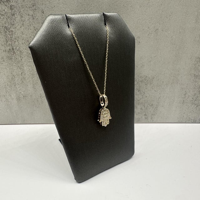 This elegant diamond Hamsa pendant necklace in 10kt yellow gold features 0.25 carats total weight of natural HI SI1–I1...