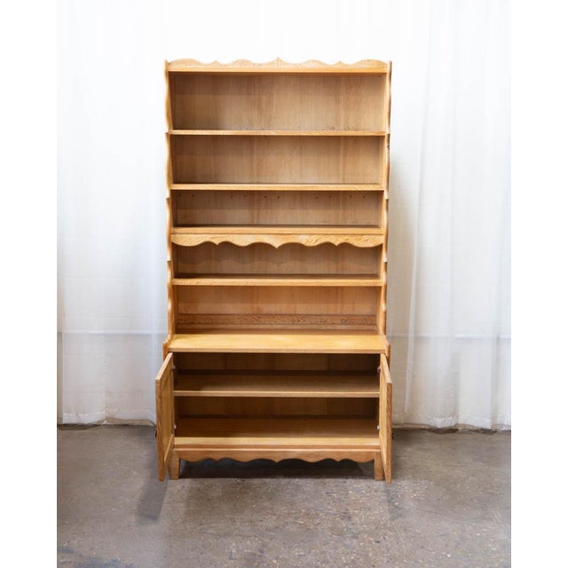 A tall Danish oak bookcase by Henning Kjærnulf, produced in the 1970s and bearing the Møbler label that confirms its...