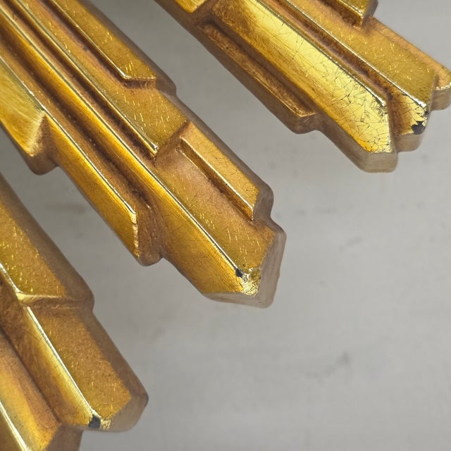 A sculptural circa-1969 Syroco starburst or sunburst wall clock with a dimensional molded-resin body, warm gold-gilt...