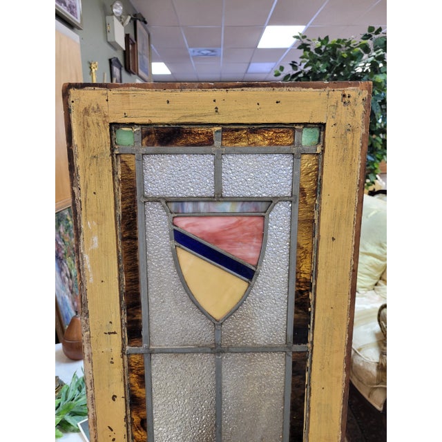 Antique coat of arms stained glass window. Features shield motif trimmed in amber glass with royal blue, green and dimpled...