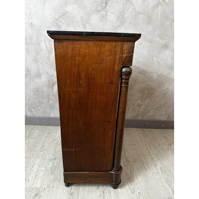 An elegant Empire-style bedside table in flamed walnut, resting on two turned columns characteristic of the style. It...
