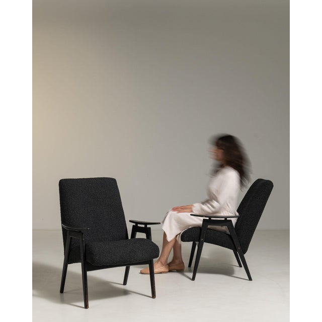 A pair of armchairs whose black upholstery, dark wood angled legs gives it real character at first glance. It was made in...