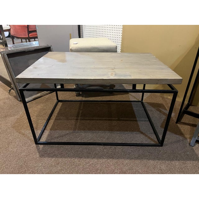 This stylish wood top coffee table featuring a warm natural wood surface paired with a sleek black metal frame. The clean...