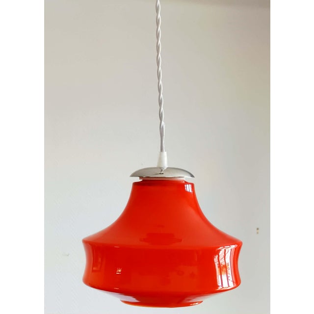 Vintage pendant light, circa 1970, featuring an orange glass globe in a UFO shape. Rewired with a new silver-plated metal...