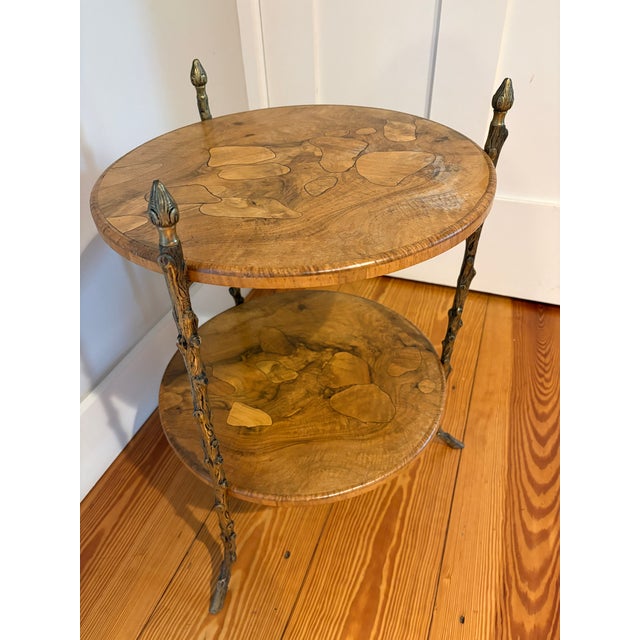 Exquisite burled walnut two tier occasional or side table by Maison Bagues. A trio of Faux Bois brass legs support the...