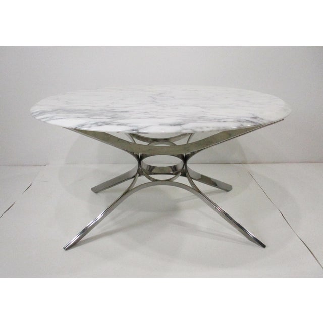 A sculptural chromed ribbon metal based coffee table with a round beveled Italian Carrera marble top . Manufactured by the...