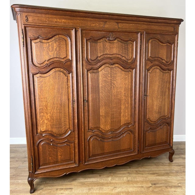 A beautiful Vintage French Louis style triple door wardrobe featuring elegant carved detailing, stunning oak grain and...