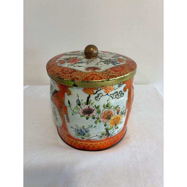 A vibrant vintage Daher canister with a rich orange and gilt chinoiserie design. White reserves frame delicate blossoms...