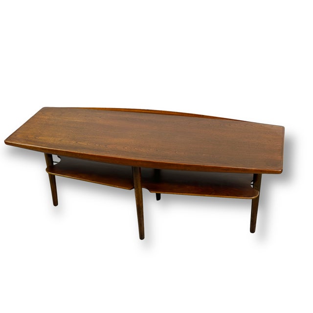 This vintage Mid-Century Modern coffee table in warm-toned oak, featuring a long, gently curved top that showcases the...