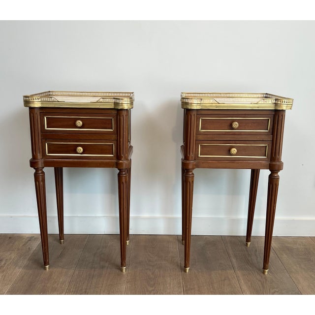 This very beautiful and elegant pair of side tables or bedside tables is made of wood and brass with white Carrara marble...